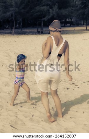 Special toned photo of young mother playing and running with daughter on the beach view 1