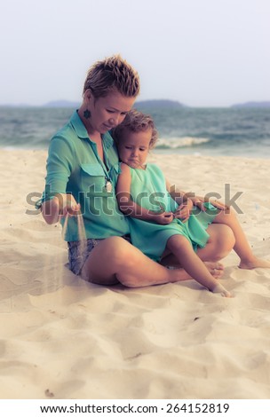 Special toned photo of young mother and daughter together on the beach dressed in similar clothes view 4
