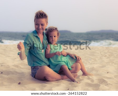 Special toned photo of young mother and daughter together on the beach dressed in similar clothes view 3