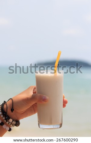 Female hand holding milk shake with tropical sea view background view 3
