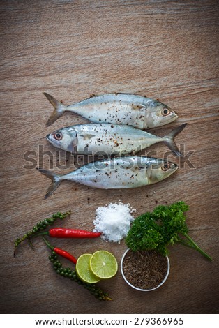 Fresh tuna with fresh pepper, salt and herbs ready for cooking on wooden background top view