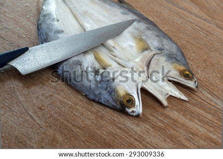 Fresh fish cut on wooden background ready for cooking with a knife, closeup