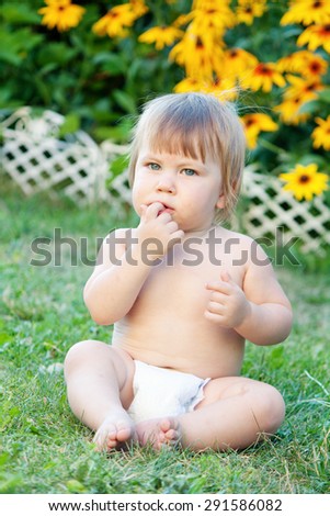Summer Baby | Small nude boy in pampers sitting on green grass in the garden with yellow flowers on background