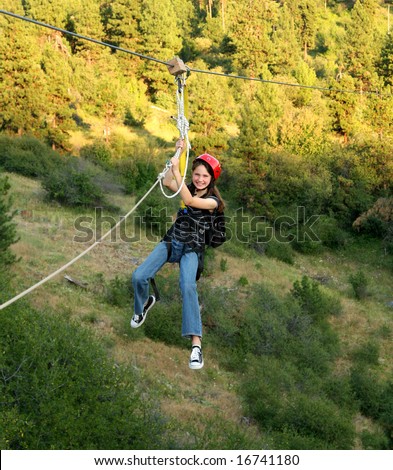 Young girl enjoying zipping (zip line) over canyon in Idaho.