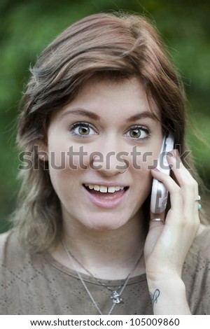 An attractive young woman smiles as she speaks on the phone, closeup