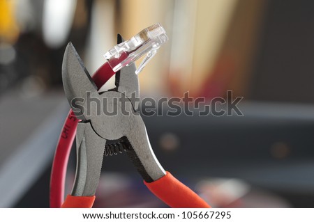 Wire cutters with bright orange handles poised to snip the end off of a cat 5 computer networking cable