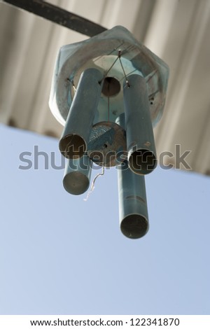 old, weathered wind chime with selective focus on old wooden spacer hanging between pipes