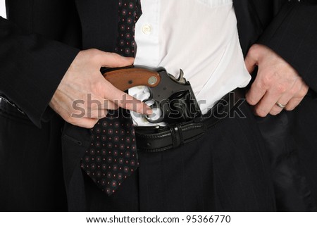 Close up of a man\'s waste, with his hand reaching for a pistol tucked into his pants