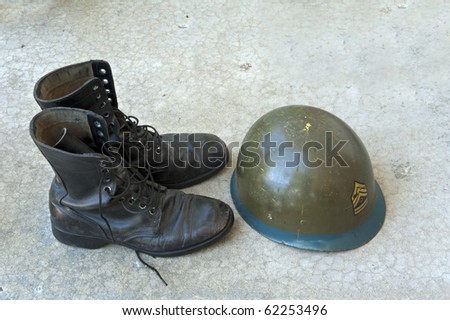 Old American military boots and helmet on concrete