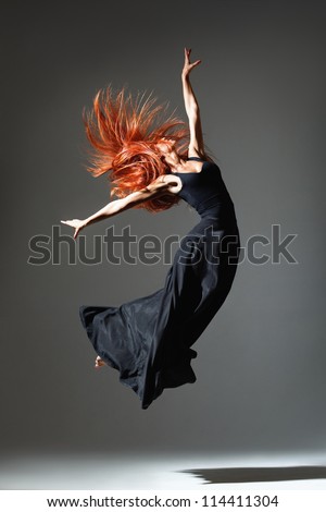 dancer with red hair jumping over dark grey background