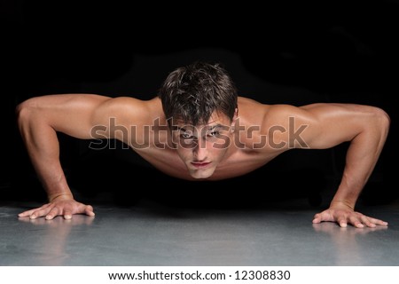 young male doing physical exersize on a dark background young male doing physical exersize on a dark background