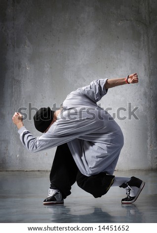 cool looking hip-hop dancer posing on old wall