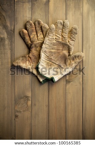 worn out working gloves against wooden surface. add your text