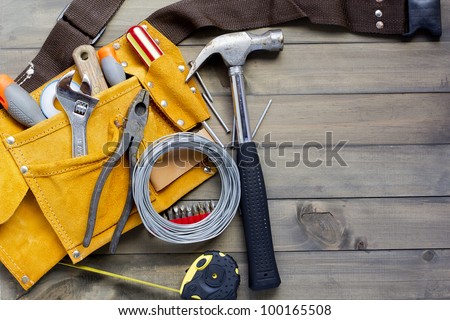 home renovation in progress. tool belt with various tools against wooden surface, add your text.