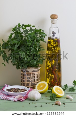 Fresh parsley, garlic, olive oil, peppercorns and lemon on a table.