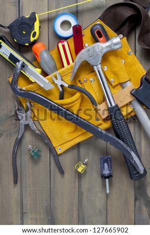 Home renovation in progress. Tool belt with various tools against wooden surface, add your text.