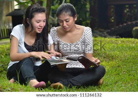 Pretty southeast asian girls  reading and sharing  information  on a book or magazine with happy expression at outdoor scene