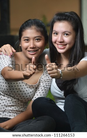 Two pretty good friends girls posing a thumb with happy expression