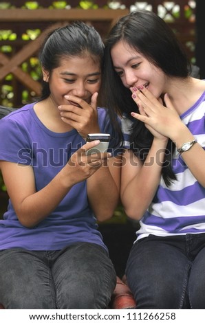 Good looking southeast asian girls sharing information on a smartphone with happy and surprise expression