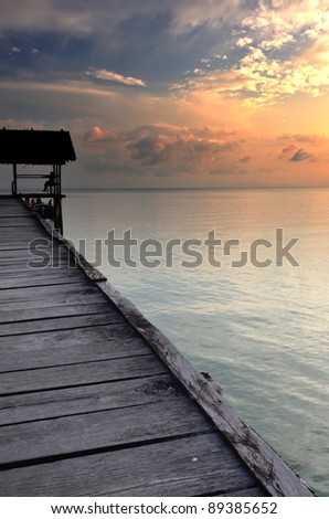Sunset on a boat dock on tropical beach with beautiful scenery. This picture taken in one of the most beautiful travel and diving destination on earth. Raja Ampat Island, Papua, Indonesia.