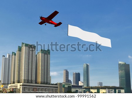 Flying banner pulled by airplane flying over a modern city building