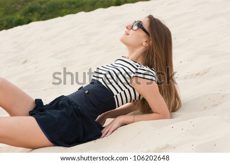 Picture of woman in dress with lines and sunglasses in the sand