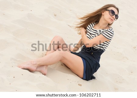 Picture of woman in dress with lines and sunglasses in the sand