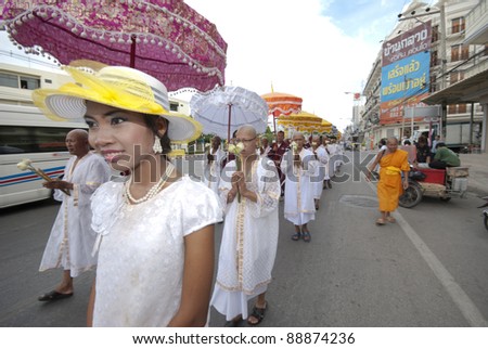 HUA HIN - OCTOBER 25. A young woman leads a procession of newly ordained Buddhist monks on October 25, 2011 in Hua Hin, Thailand. Monk ordinations in Thailand are very important social events.