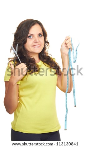 Attractive smiling girl in a yellow shirt holding a scissors in the right hand and in the left hand holds a centimeter. Isolated on white background