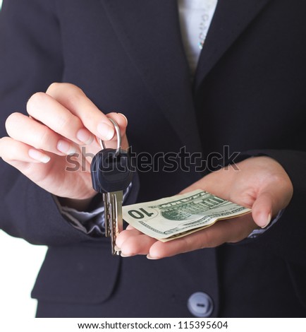 Manicured hands of a young girl in a black business suit. In her right hand located the keys in the left hand are dollars. Isolated on white background