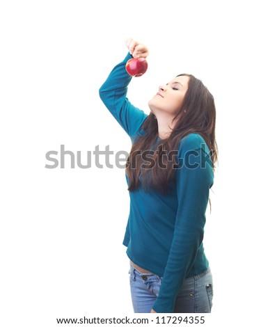 Attractive young woman in a blue shirt holding in her right hand a beautiful red apple and sniffs it. Isolated on white background