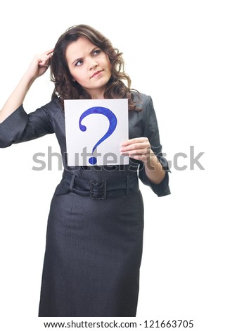 Attractive smiling young woman in a gray business dress holding a poster with a big question mark, and looks to the upper-left corner. Isolated on white background