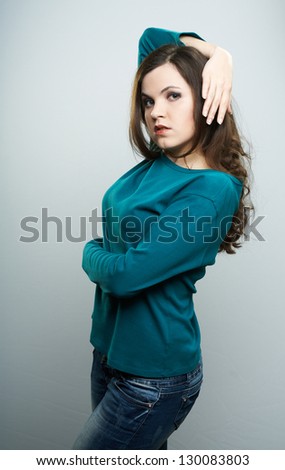Attractive young woman in a blue shirt. Woman holds her hand over her head. On a gray background