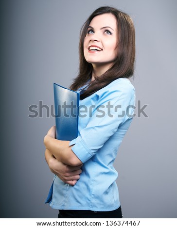 Attractive young woman in a blue blouse. Woman holds a blue folder. On a gray background