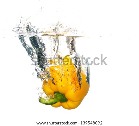Fresh yellow pepper falling in water with a splash of water. Isolated on white background