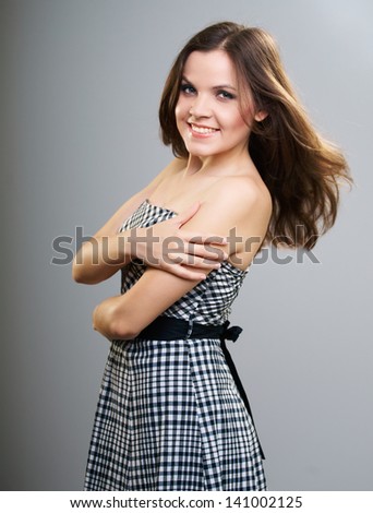 Attractive young woman in a plaid dress. Hair in motion. Isolated on a gray background