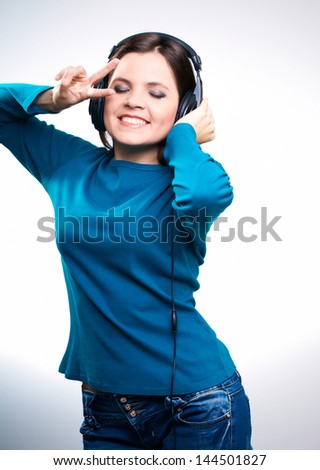 Attractive young woman in a blue shirt. Woman with headphones listening to music and dances. On a white background