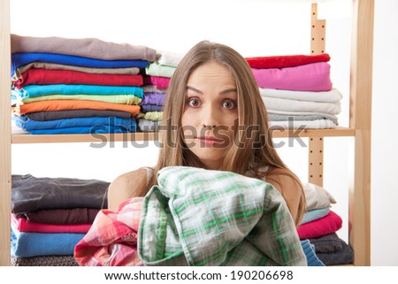 young woman holding a pile of clothes, isolated on white background