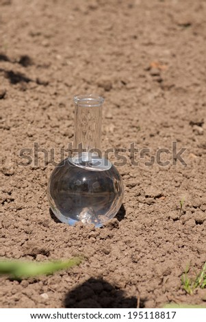 flask with clear water or fertilizer on dry soil