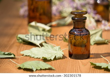 essential oil in little bottle and medical flowers herbs on wooden board