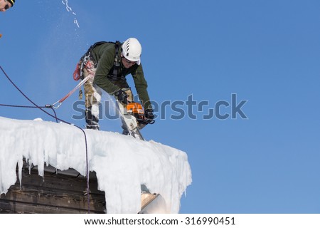 SOCHI, RUSSIA - JANUARY 22, 2015: Industrial climber take off the snow and icicles from the roof