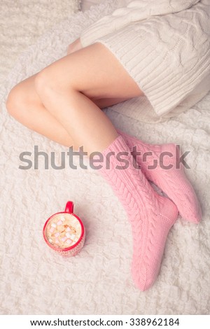 legs of girl in warm woolen socks and a cup of coffee warming, winter morning at home