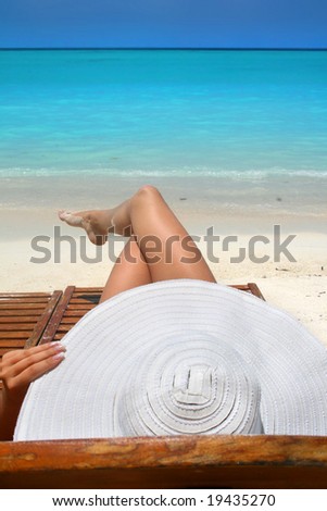 woman with big white hat relaxing on the beach