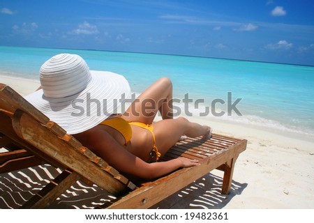 woman with big white hat relaxing on the beach