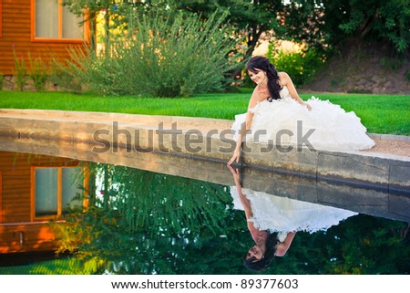 beautiful bride in wedding dress with reflection on the water