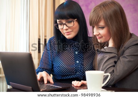 two women in cafe look in laptop