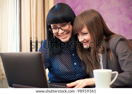 two women in cafe look in laptop