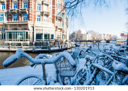 Bicycles covered with snow on a bridge during winter in Amsterda