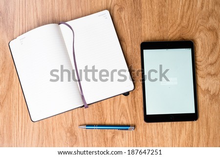 Open notebook and an tablet on a desk. Front of the both items is blank