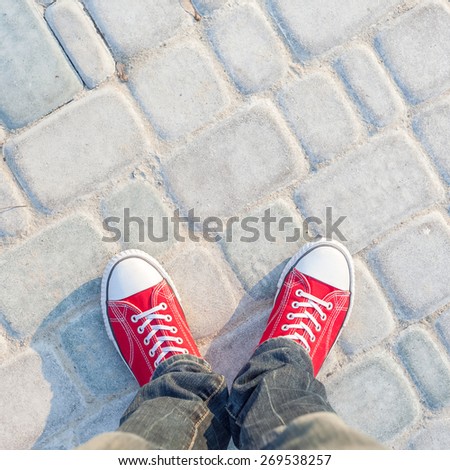 young man feet in red sneakers on cobbled road